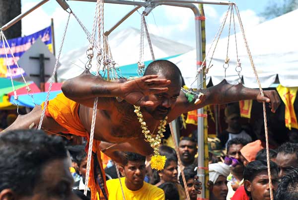 A devotee fulfils his vows by hanging on hooks pierced through his skin during Thaipusam at Batu Caves