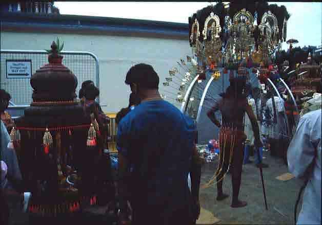 A devotee pulling a small chariot hooked to his back in addition to carrying a kavadi