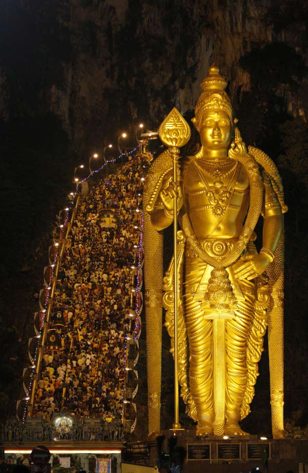 Hindu devotees climb 272 steps to the Batu Caves temple next to a giant statue of Lord Murugan during the Thaipusam festival